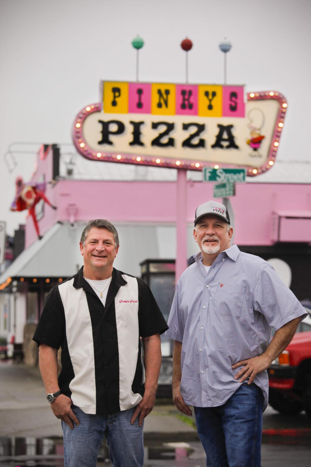 two men standing in front of pinkys pizza sign