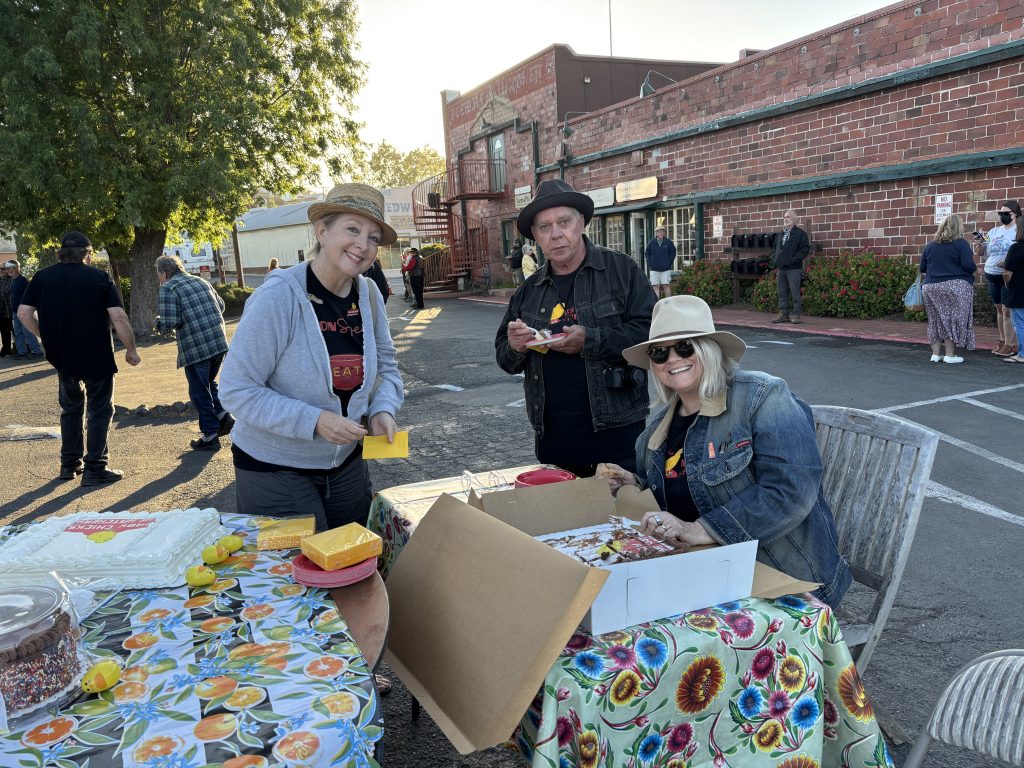 Heather David, Al Barna, and Randall Ann Homan are posing in front of the cake table during the June 14, 2026, sign lighting event. Photo taken by Katherine J. Rinehart